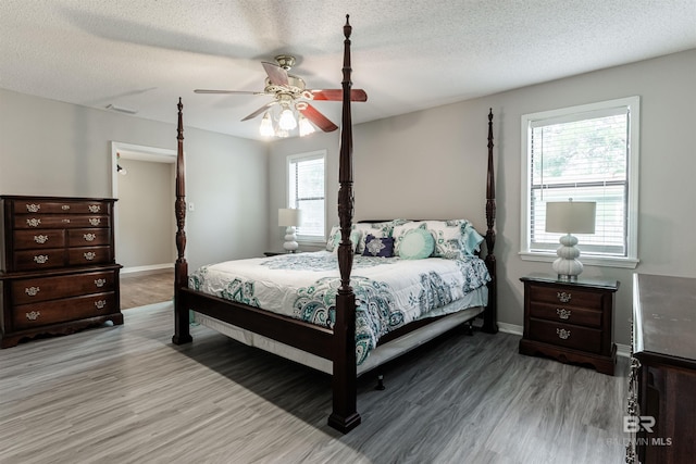 bedroom featuring ceiling fan, hardwood / wood-style flooring, and a textured ceiling