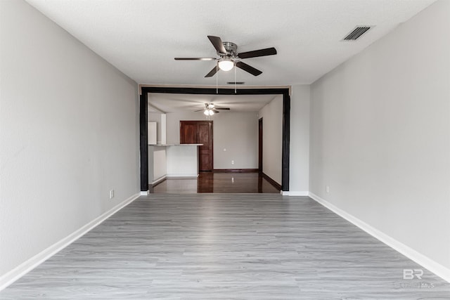 spare room with ceiling fan, a textured ceiling, and light wood-type flooring