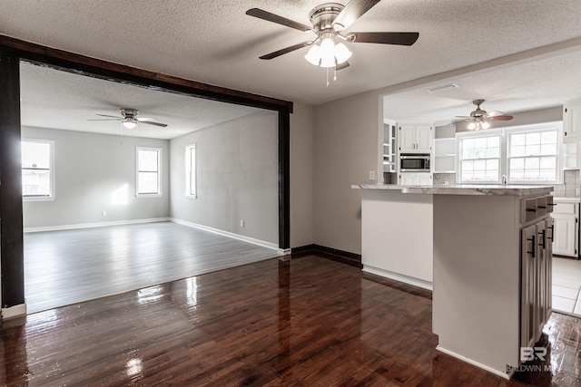 kitchen featuring ceiling fan, a textured ceiling, white cabinetry, stainless steel microwave, and dark hardwood / wood-style floors