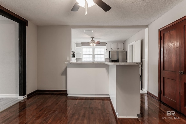 kitchen with a textured ceiling, stainless steel refrigerator with ice dispenser, white cabinets, and dark wood-type flooring