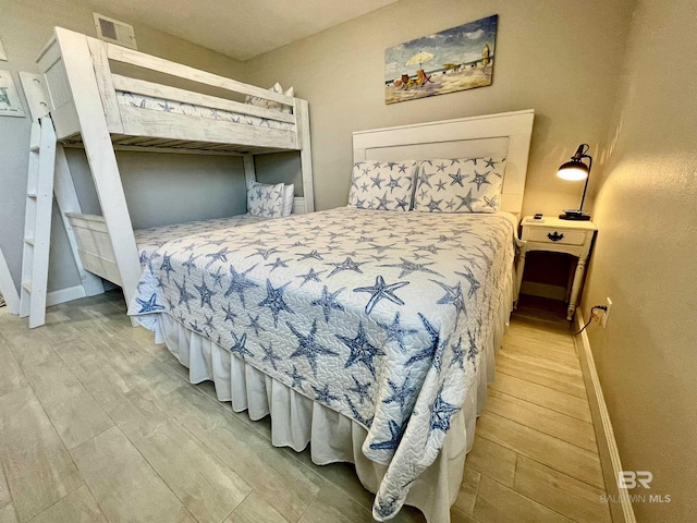 bedroom with wood finished floors, visible vents, and baseboards