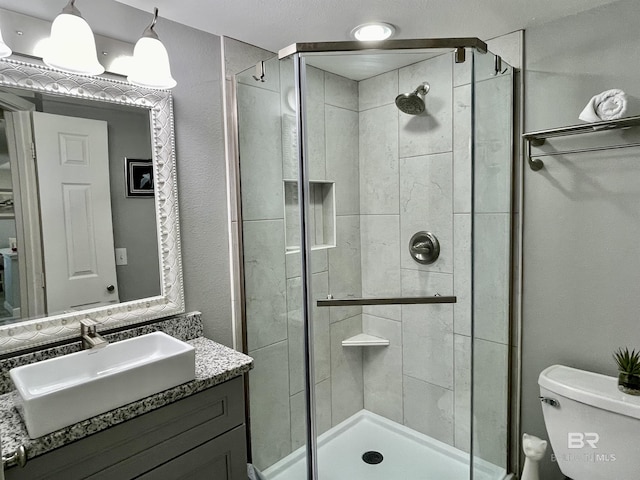 full bath with vanity, a shower stall, and toilet