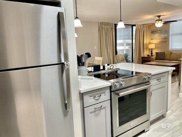 kitchen with stainless steel appliances, open floor plan, light countertops, and light wood-style floors