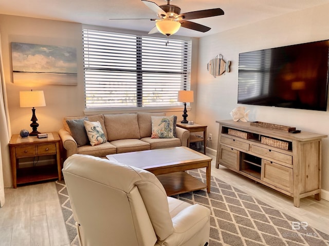 living area featuring light wood-style flooring, baseboards, and a ceiling fan