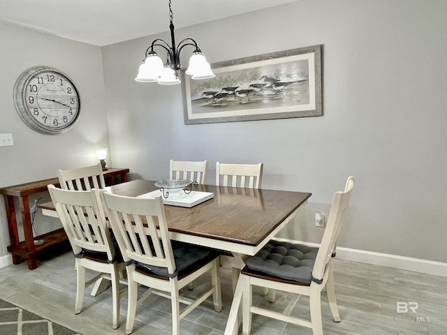 dining room with a notable chandelier, light wood finished floors, and baseboards