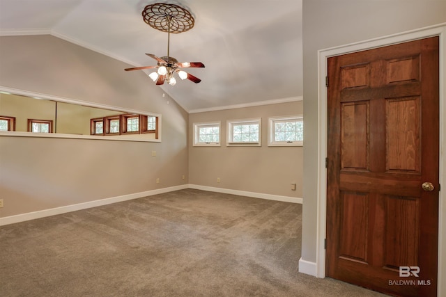 carpeted empty room featuring crown molding, vaulted ceiling, and ceiling fan