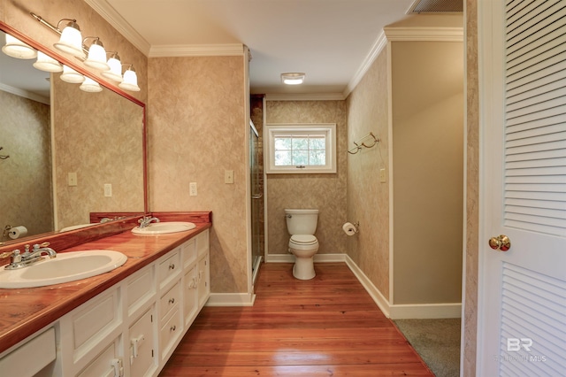 bathroom featuring hardwood / wood-style flooring, a shower with door, crown molding, toilet, and vanity