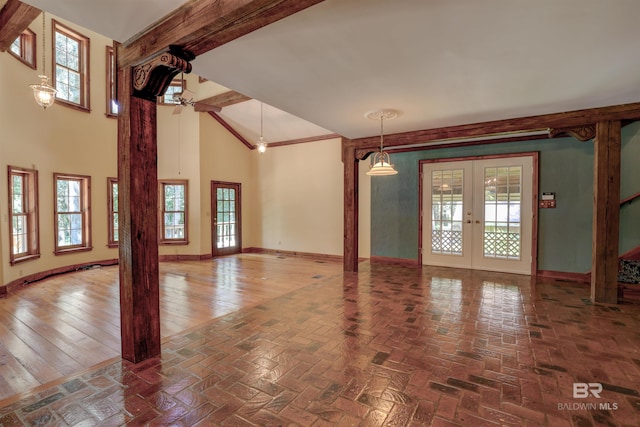 unfurnished living room with a towering ceiling, hardwood / wood-style floors, and french doors