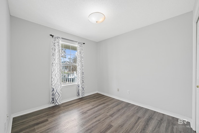 empty room with dark wood-style floors, a textured ceiling, and baseboards