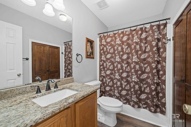 full bath with vanity, wood finished floors, visible vents, a textured ceiling, and toilet