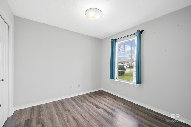 empty room featuring dark wood finished floors and baseboards