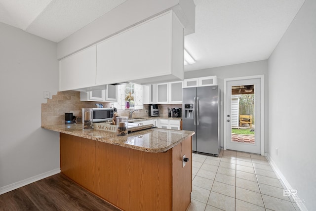 kitchen featuring a peninsula, plenty of natural light, a sink, stainless steel appliances, and tasteful backsplash