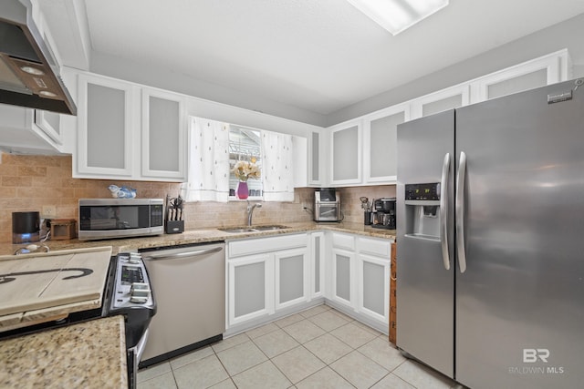 kitchen featuring tasteful backsplash, appliances with stainless steel finishes, extractor fan, and a sink