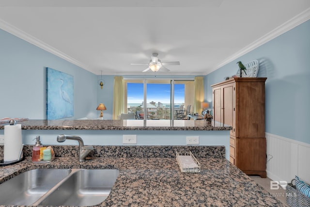453 Dune Dr Unit 305, Gulf Shores, AL 36542 - kitchen featuring a sink, ceiling fan, wainscoting, ornamental molding, and dark stone counters