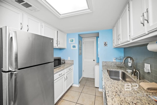 327 E Beach Blvd Unit 7C, Gulf Shores, AL 36542 - kitchen featuring appliances with stainless steel finishes, a sink, backsplash, and white cabinets