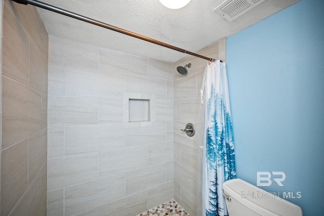 327 E Beach Blvd Unit 7C, Gulf Shores, AL 36542 - full bath with a tile shower, toilet, and a textured ceiling