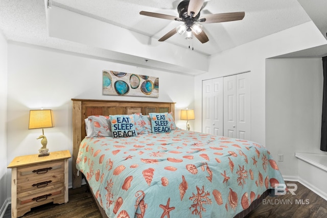 bedroom with ceiling fan, dark hardwood / wood-style floors, a closet, and a textured ceiling