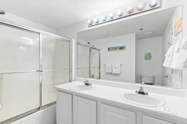 full bathroom with vanity, a textured ceiling, enclosed tub / shower combo, and toilet