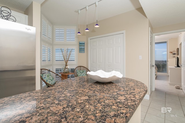 tiled dining area featuring a towering ceiling and rail lighting