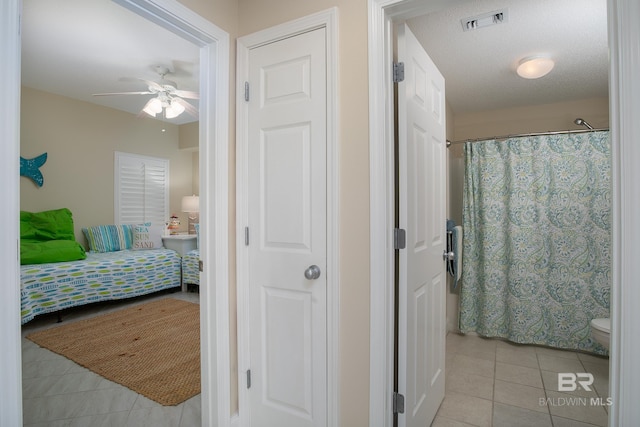 tiled bedroom featuring ceiling fan and a textured ceiling