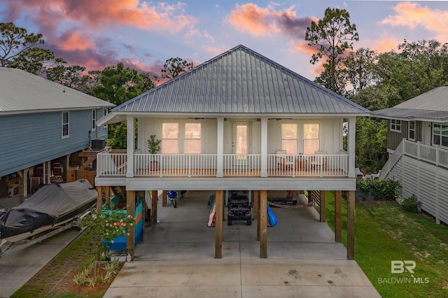 back house at dusk with a carport, covered porch, and central air condition unit