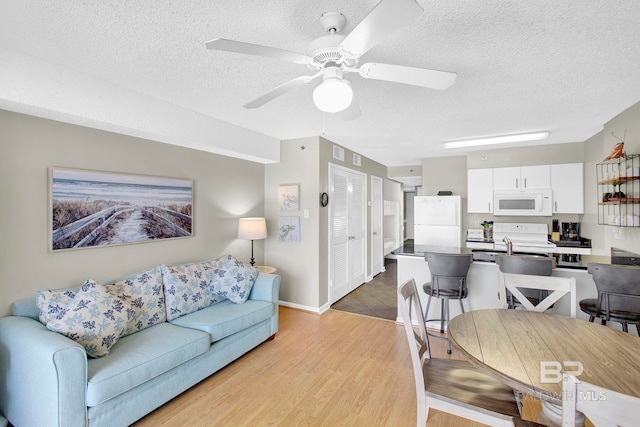 24568 Perdido Beach Blvd Unit 603, Orange Beach, AL 36561 - living area featuring a textured ceiling, light wood-type flooring, ceiling fan, and baseboards
