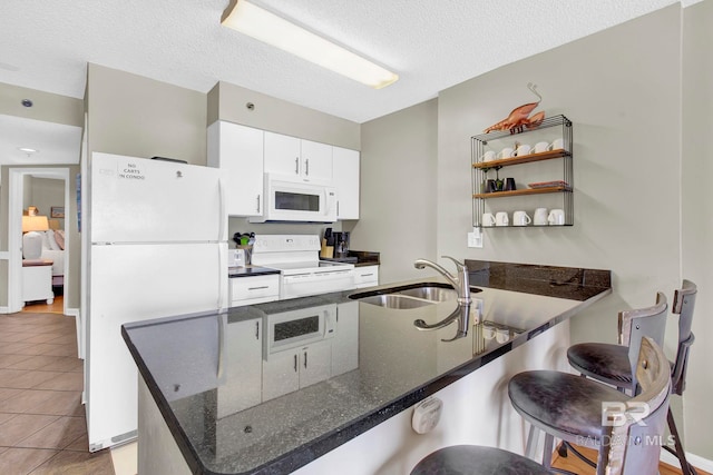 24568 Perdido Beach Blvd Unit 603, Orange Beach, AL 36561 - kitchen featuring white appliances, a sink, a breakfast bar, a peninsula, and light tile patterned floors