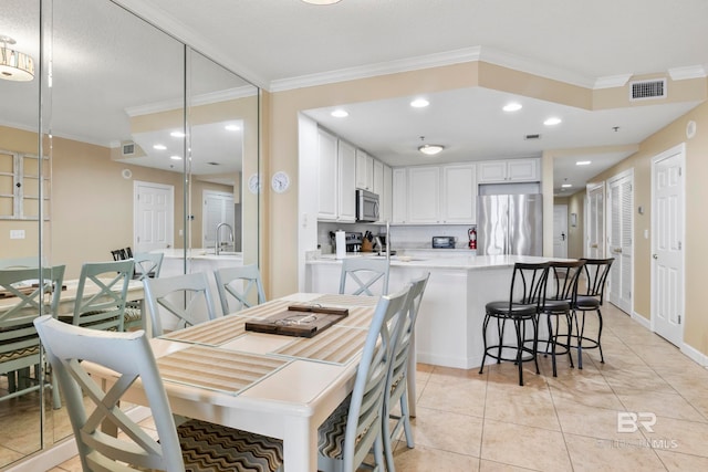 tiled dining space with crown molding and sink