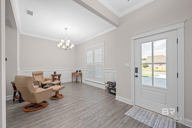 foyer featuring ornamental molding, light hardwood / wood-style flooring, and a notable chandelier