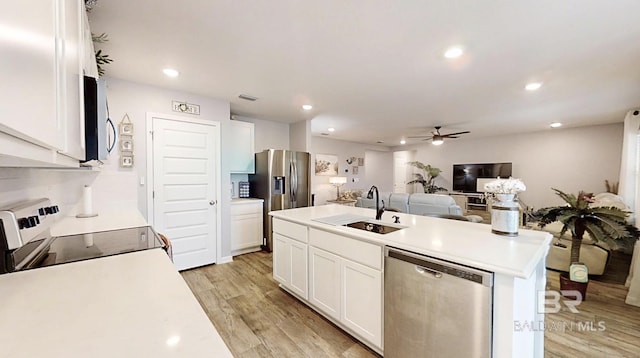 kitchen featuring appliances with stainless steel finishes, light wood-type flooring, white cabinets, and a sink