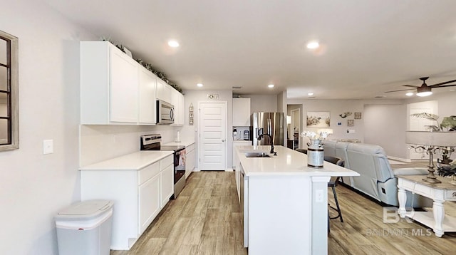 kitchen featuring light wood-style flooring, appliances with stainless steel finishes, a breakfast bar, and a sink