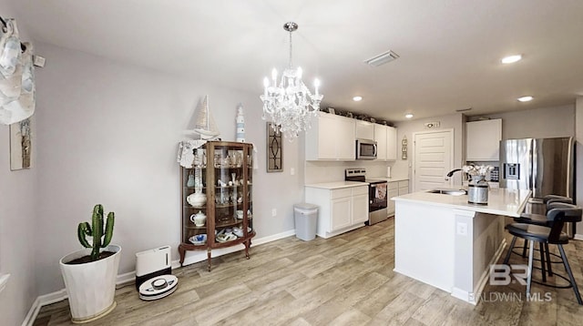 kitchen with light countertops, appliances with stainless steel finishes, light wood-style floors, a sink, and a kitchen breakfast bar