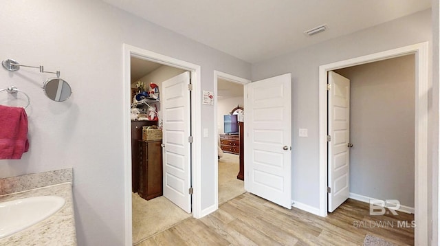 bathroom with baseboards, visible vents, wood finished floors, and vanity