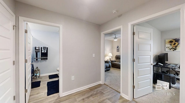 hallway with light wood-type flooring and baseboards