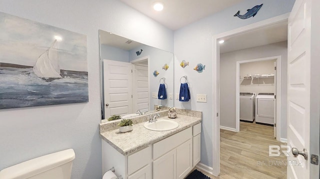 bathroom with washer and clothes dryer, toilet, vanity, wood finished floors, and baseboards