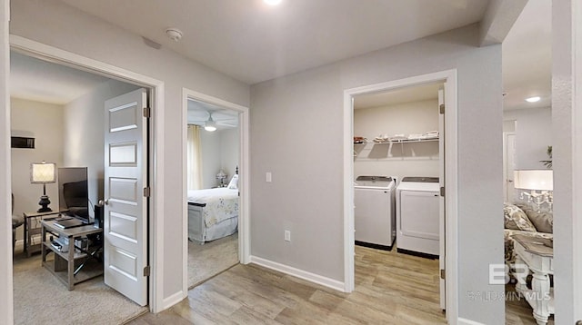 corridor with baseboards, light wood-style flooring, and washing machine and clothes dryer