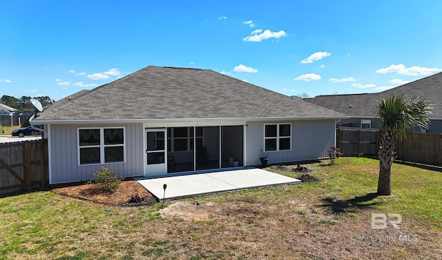 rear view of property featuring roof with shingles, a lawn, a sunroom, a patio area, and a fenced backyard