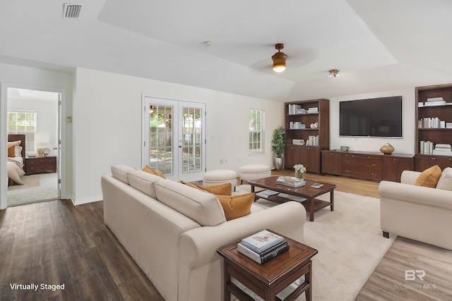 living area featuring a tray ceiling, plenty of natural light, wood finished floors, and visible vents