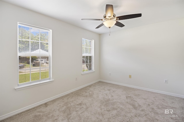 carpeted empty room with a ceiling fan and baseboards