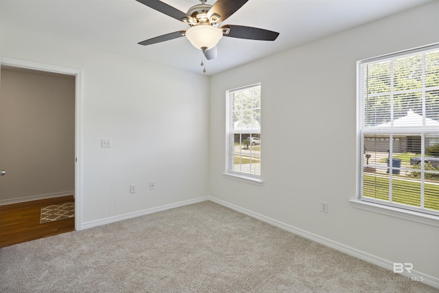 empty room with carpet flooring, a ceiling fan, and baseboards