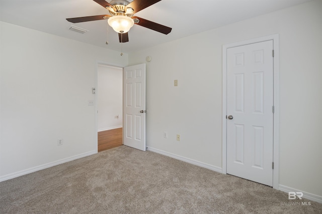 carpeted spare room featuring a ceiling fan, visible vents, and baseboards