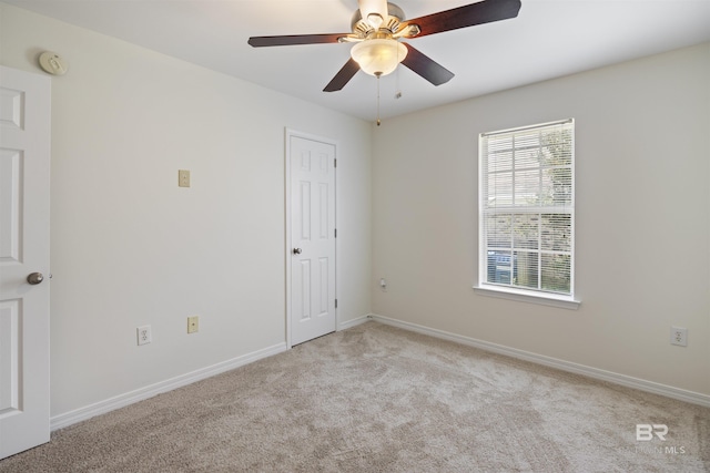 carpeted spare room featuring ceiling fan and baseboards