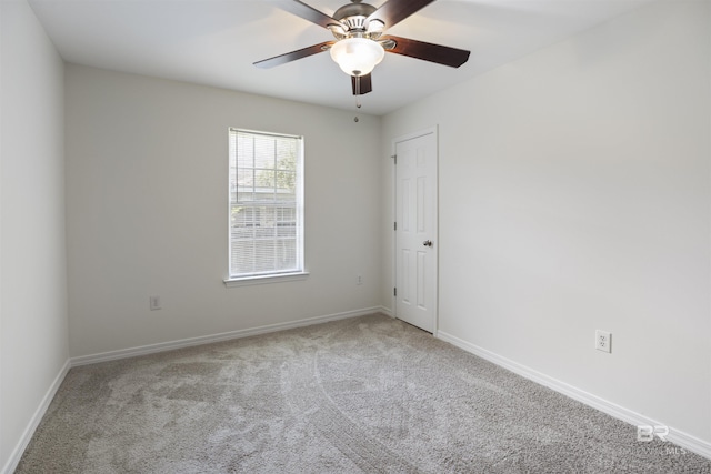 carpeted spare room with a ceiling fan and baseboards