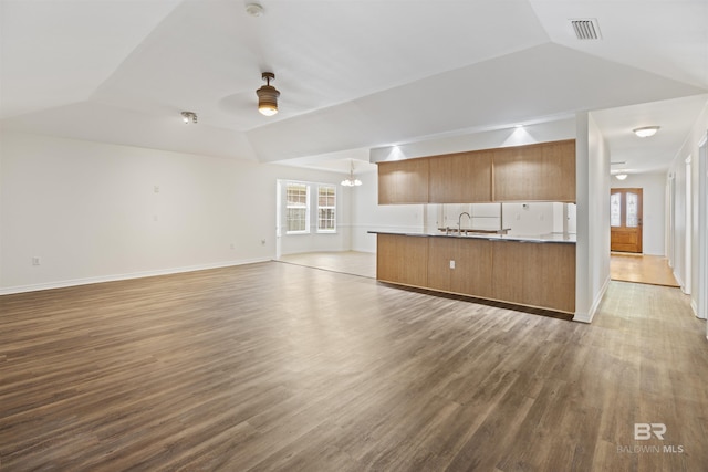 kitchen featuring ceiling fan with notable chandelier, wood finished floors, visible vents, open floor plan, and brown cabinetry