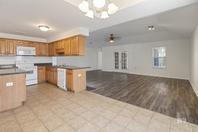 kitchen with light tile patterned floors, open floor plan, a sink, white appliances, and ceiling fan with notable chandelier