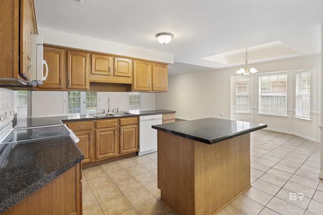 kitchen featuring a center island, light tile patterned floors, dark countertops, a sink, and white appliances