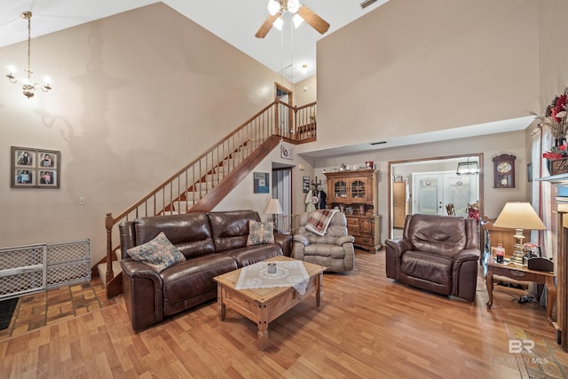 living room with high vaulted ceiling, ceiling fan with notable chandelier, and light wood-type flooring