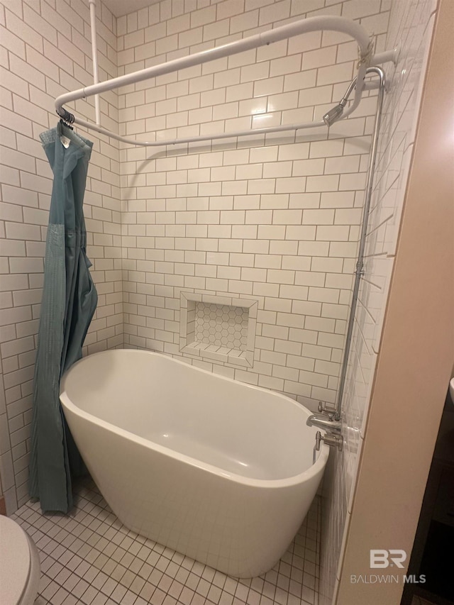 bathroom featuring tiled shower / bath combo, toilet, and tile patterned floors