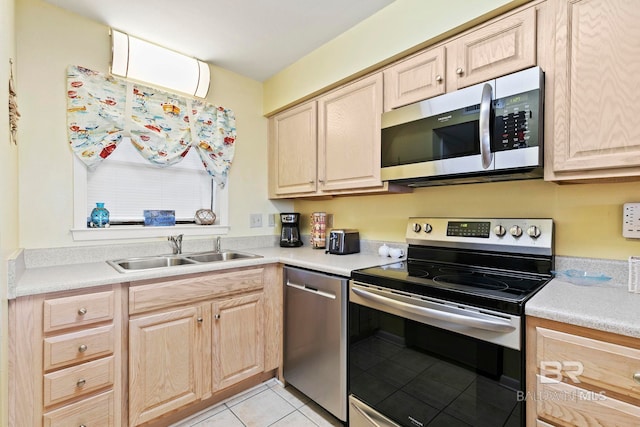 kitchen featuring stainless steel appliances, light brown cabinets, sink, and light tile patterned floors