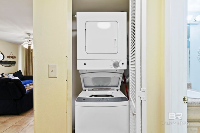 clothes washing area featuring stacked washing maching and dryer, ceiling fan, and light tile patterned floors